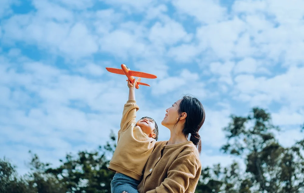 Une mère et un jeune enfant jouent dehors avec un petit avion