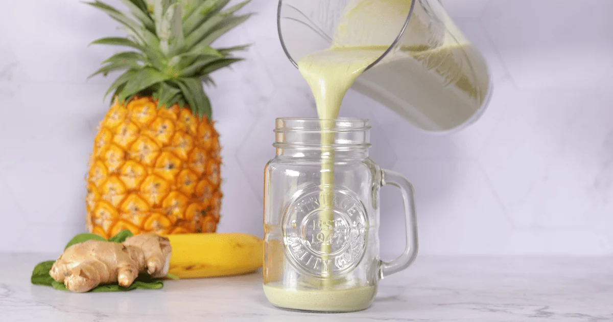 Une boisson est versée dans un verre à côté d’un ananas
