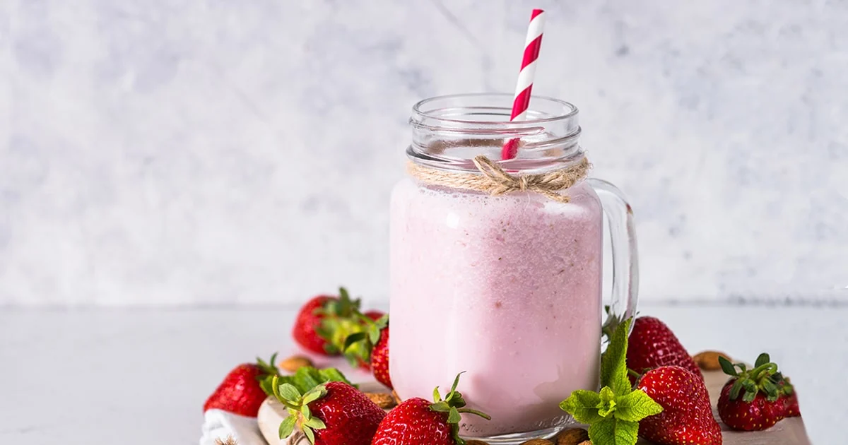 Un smoothie rose accompagné de fraises sur une table